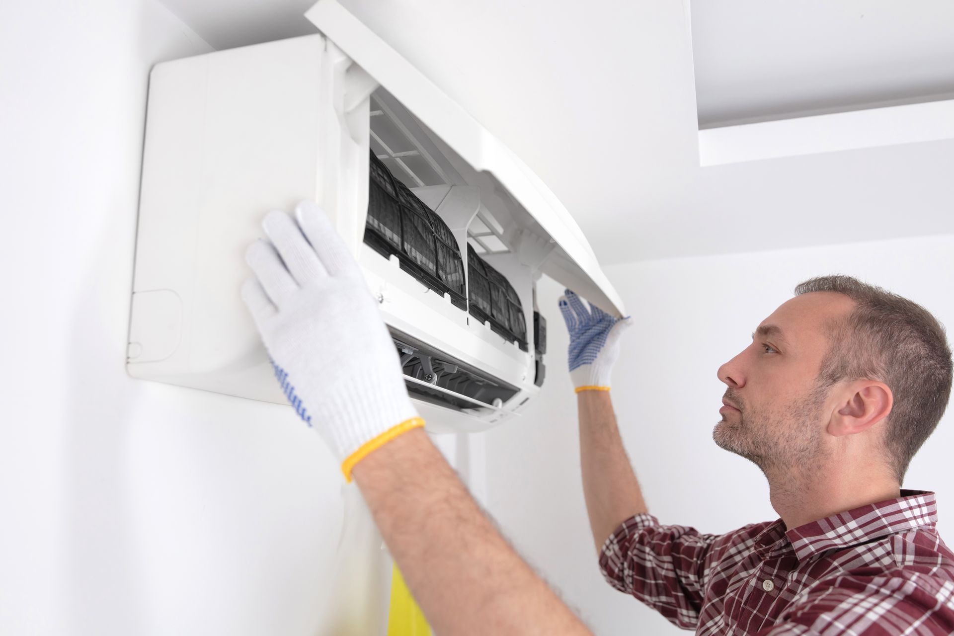 A man is cleaning the filter of an air conditioner.