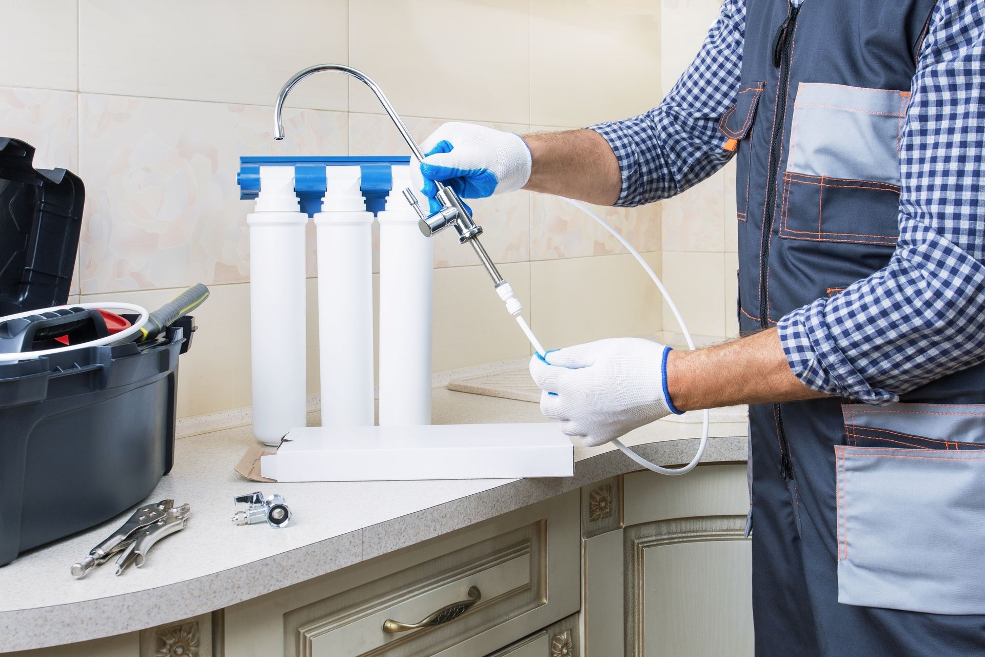 A man is fixing a water filter in a kitchen.