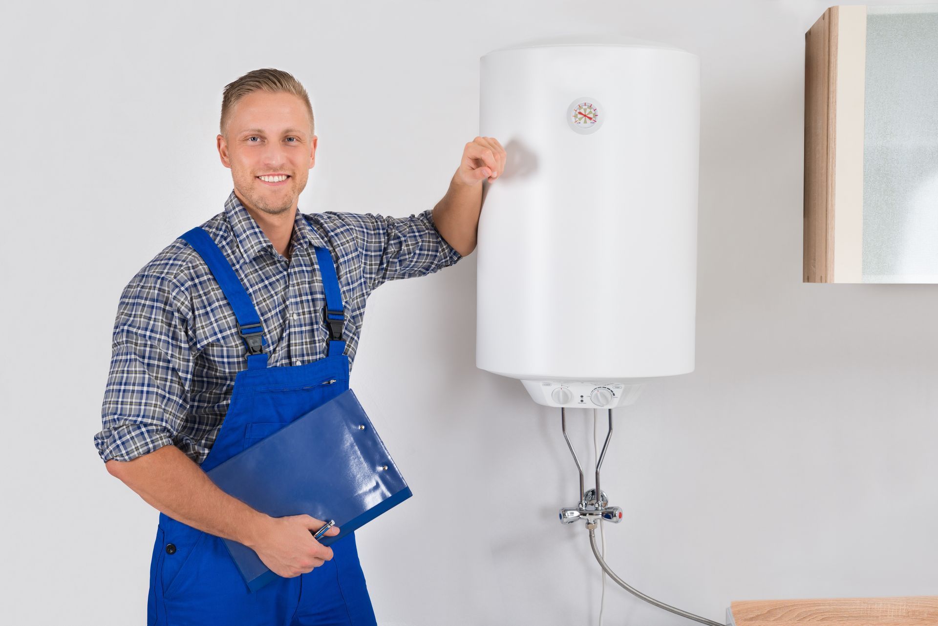 A man is standing next to a water heater holding a clipboard.