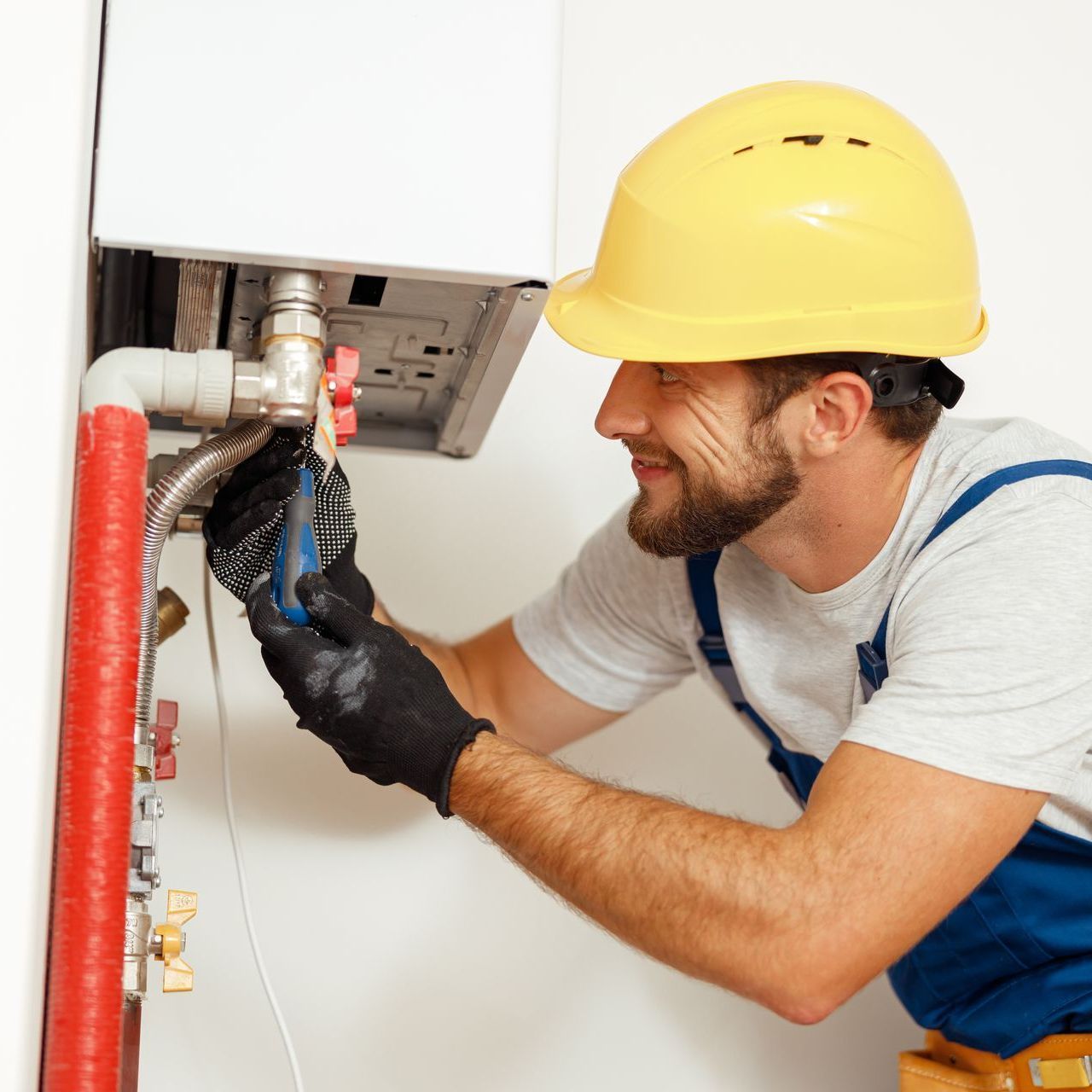 A man wearing a yellow hard hat is working on a pipe
