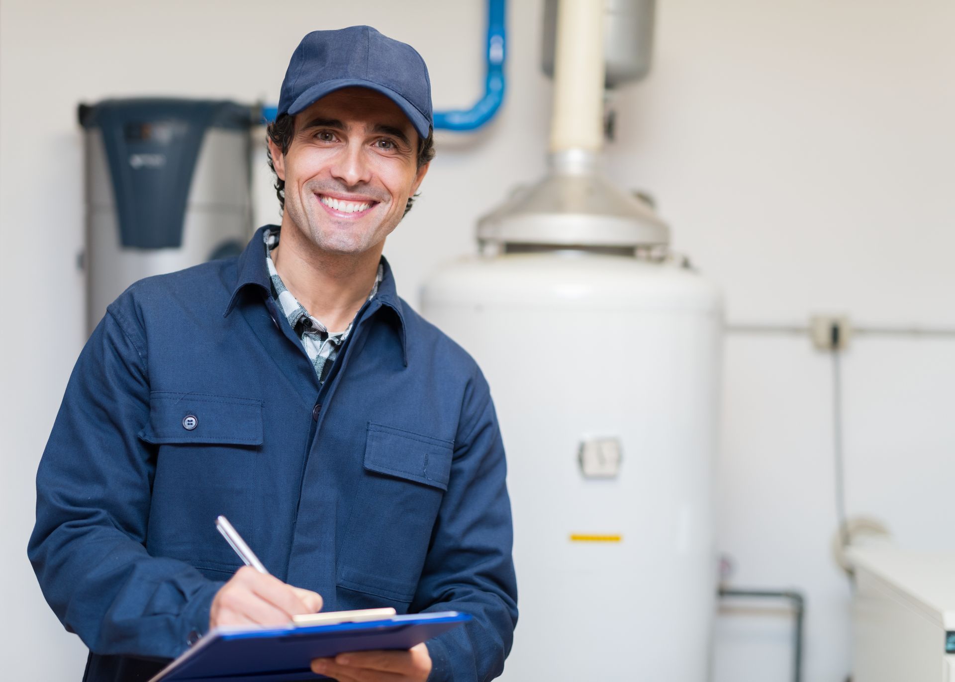 A man is holding a clipboard and smiling in front of a water heater.