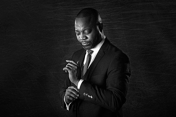 A man in a suit and tie is adjusting his cufflinks.