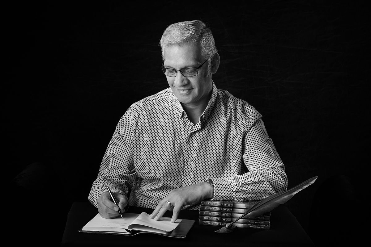 A man is sitting at a table writing on a piece of paper.