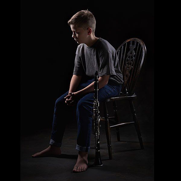 teenage boy leaning forward sitting on wheel back chair Oakley Studios celebration photoshoot in Luton Bedfordshire