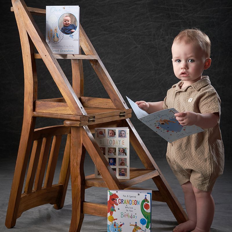 A little boy is standing on a wooden ladder