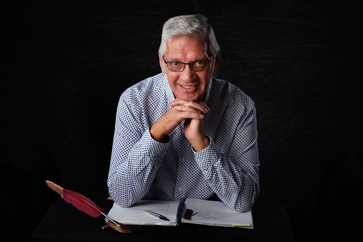 A man is sitting at a table with a pen and a notebook.