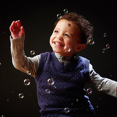 boy smiling chasing bubbles Oakley Studios celebration photoshoot in Luton Bedfordshire