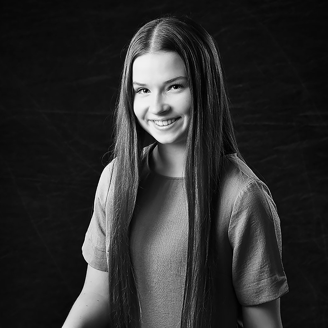 A woman with long hair is smiling in a black and white photo.