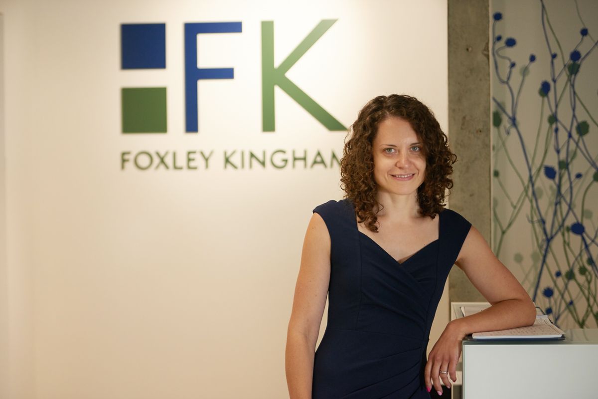 A woman stands in front of a foxley kingham sign