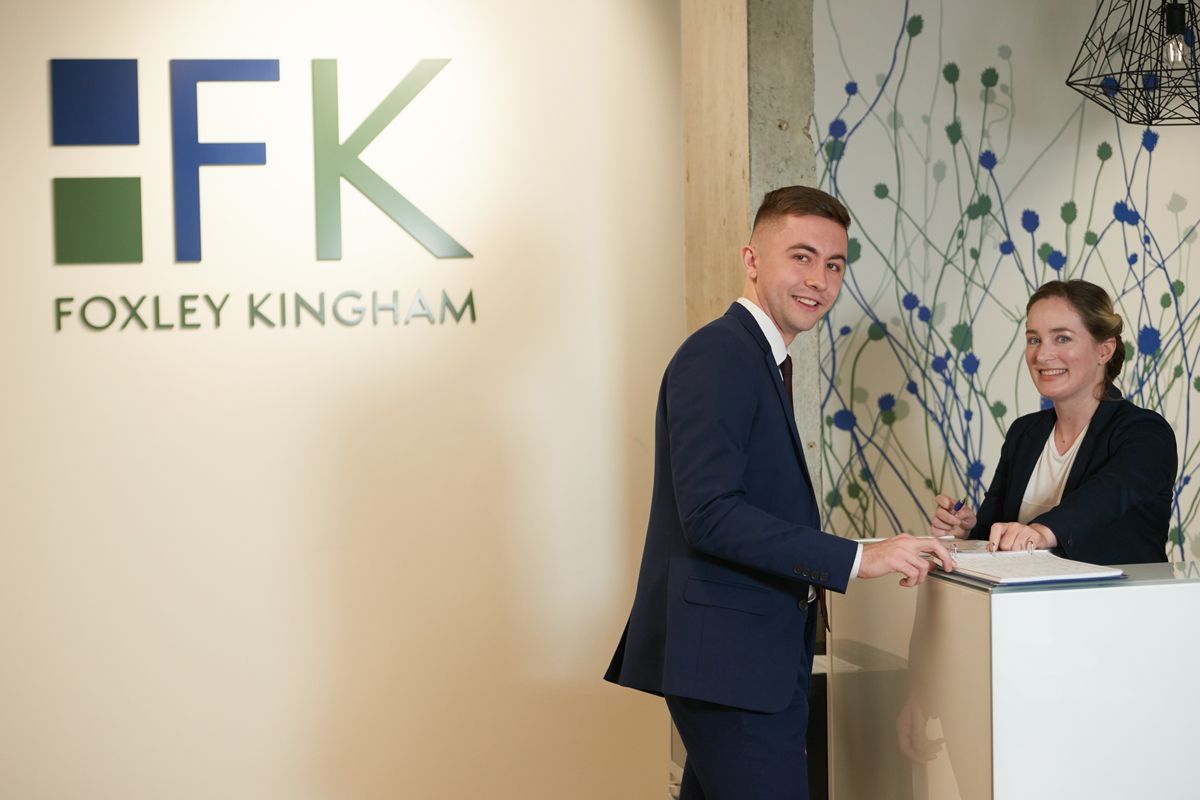A man and a woman are standing in front of a foxley kingham sign.