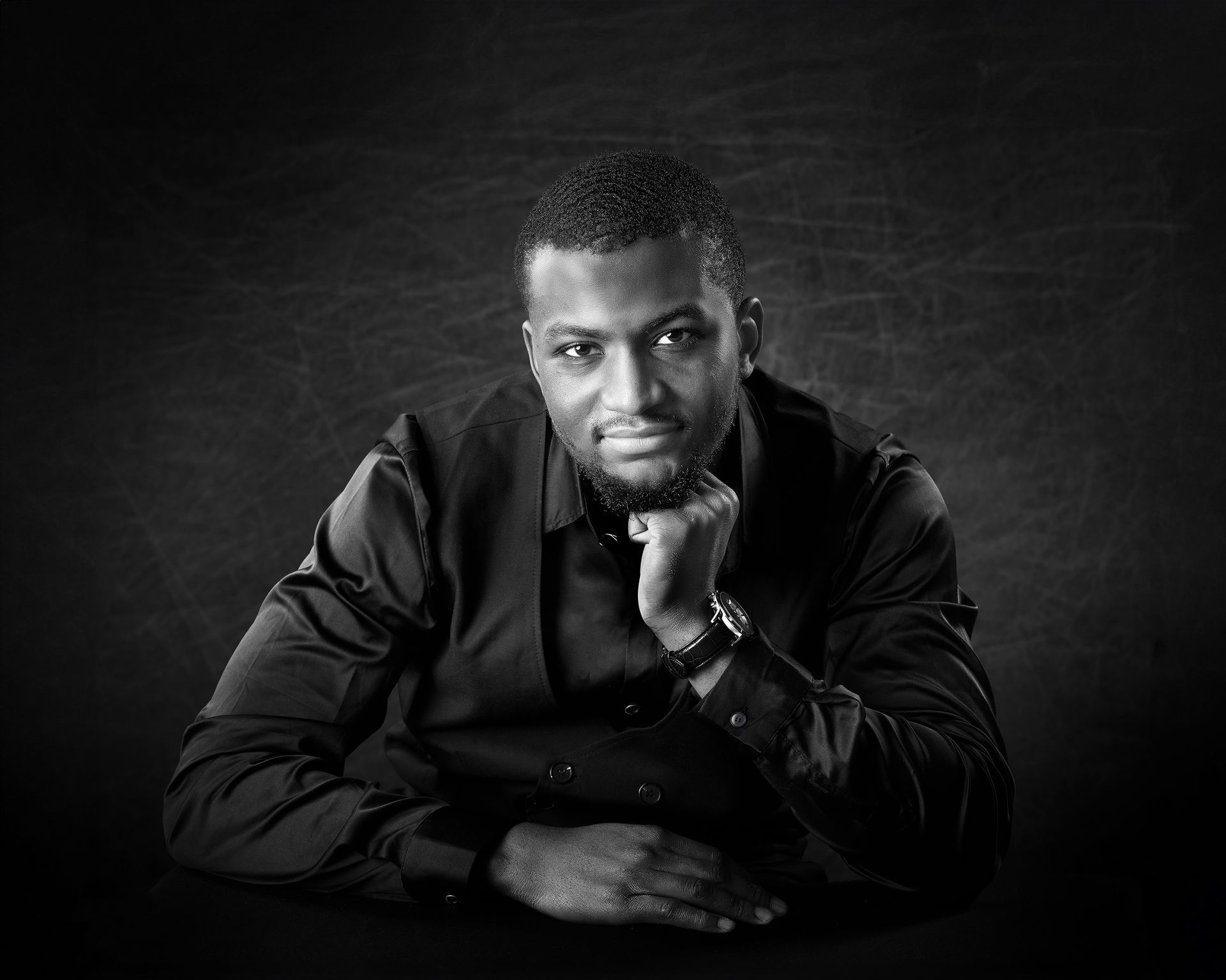 A black and white photo of a man with his hand on his chin.