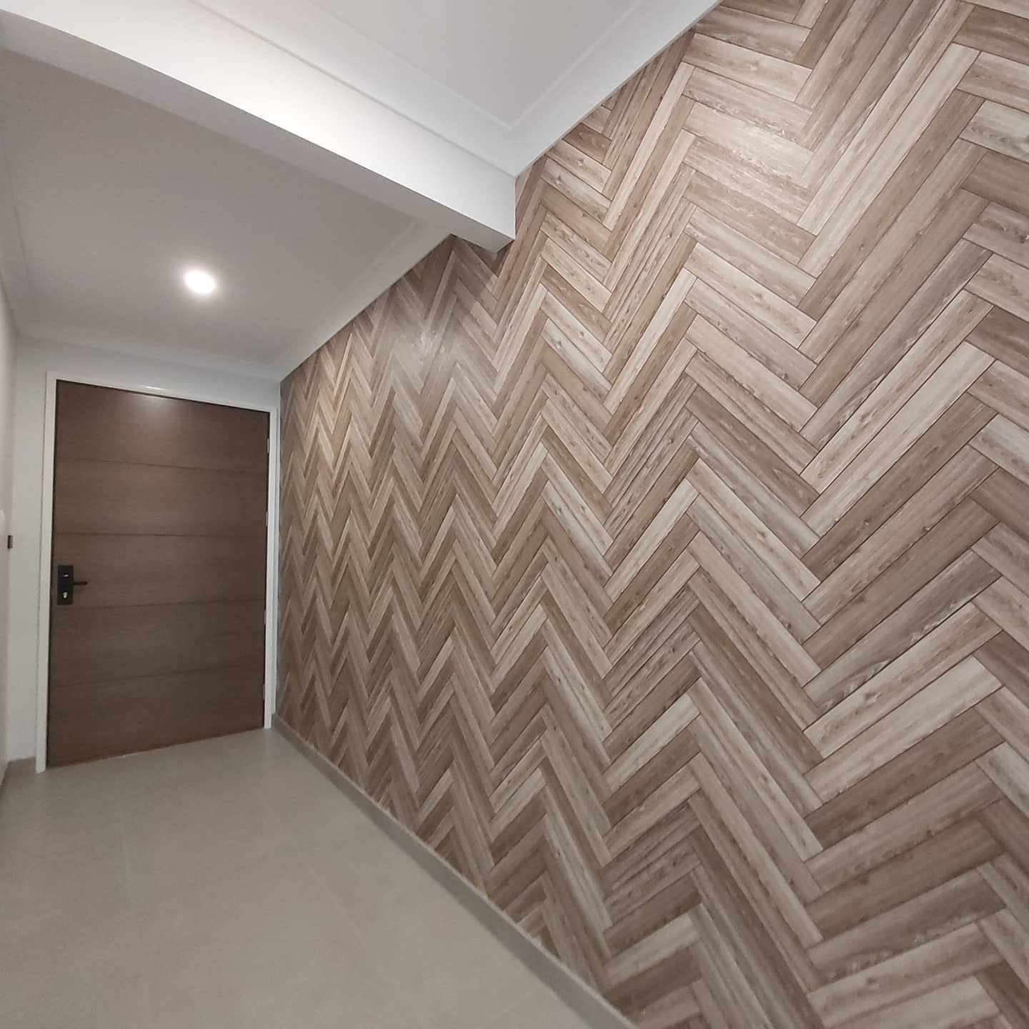 Modern hallway featuring herringbone wood wallpaper accent wall, neutral tones, recessed lighting