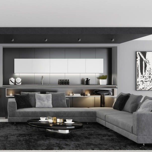 Modern living room with gray sectional sofa, black coffee table, and minimalist kitchen.