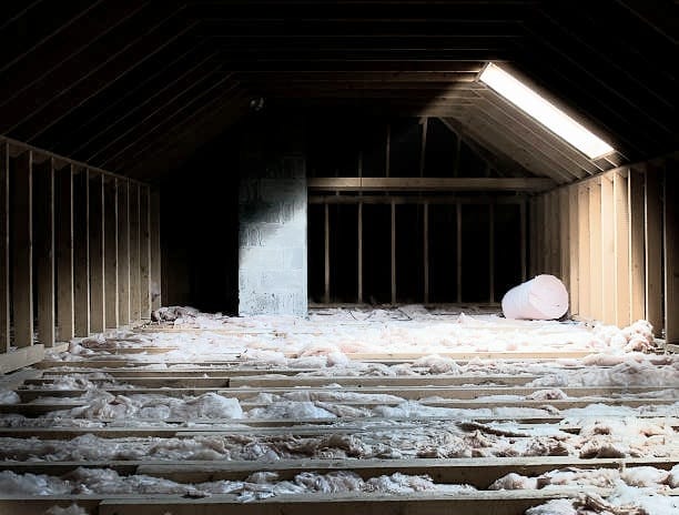 Attic interior, wooden frame, insulation, central chimney, sunlight.