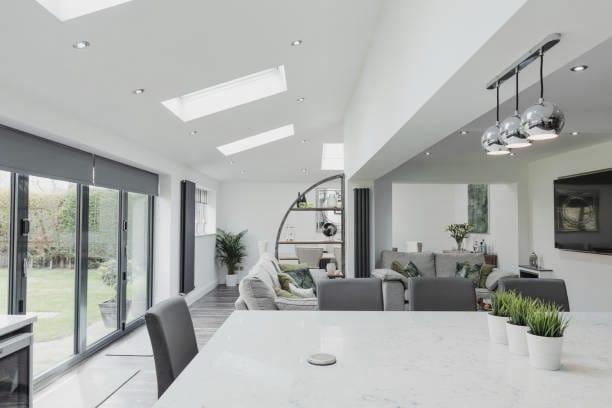 Modern open-plan kitchen and living area with skylights and large glass doors overlooking a garden.
