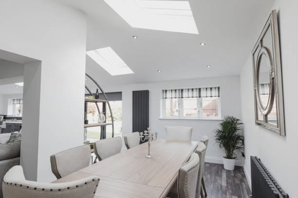 Bright dining room with long wooden table, skylights, and neutral colored chairs.