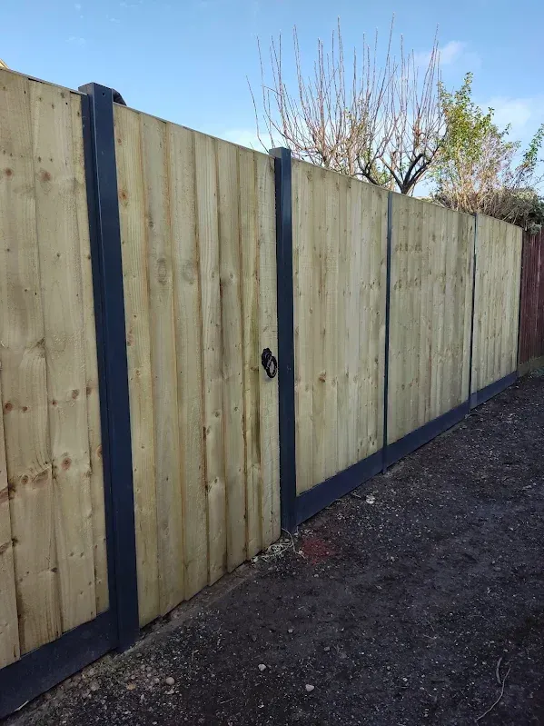 Wooden fence with dark grey frame, with a closed gate.