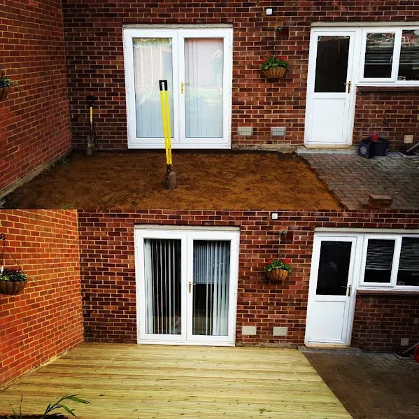 Before and after of a backyard patio transformation: dirt to wooden deck, brick walls, white doors.