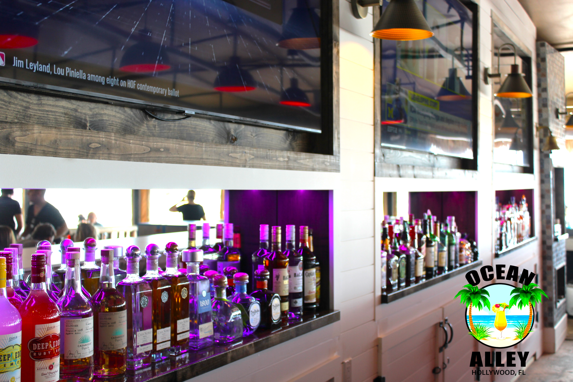A bar filled with lots of bottles of alcohol and a sign that says ocean alley