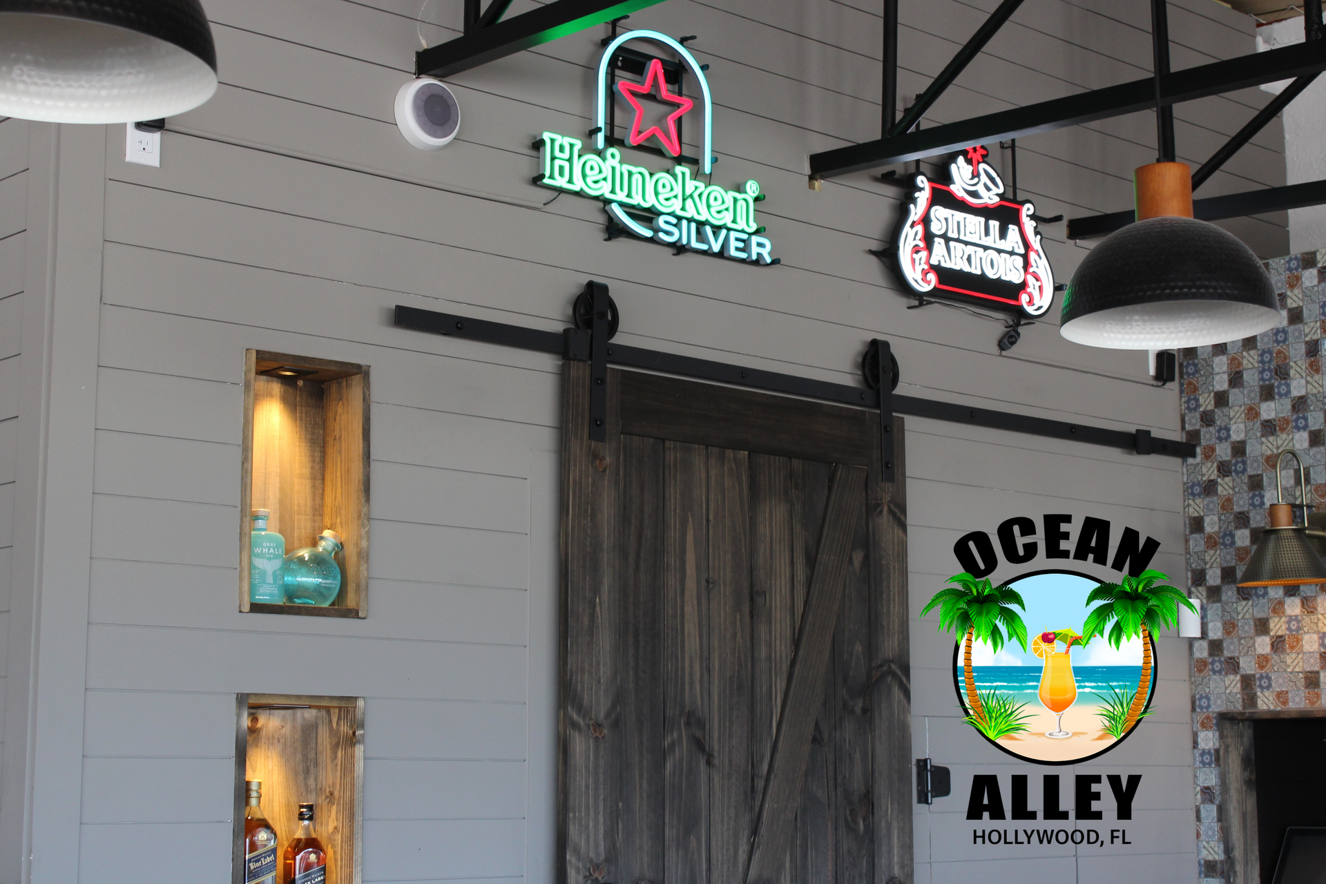 A restaurant with a sliding barn door and neon signs on the wall.