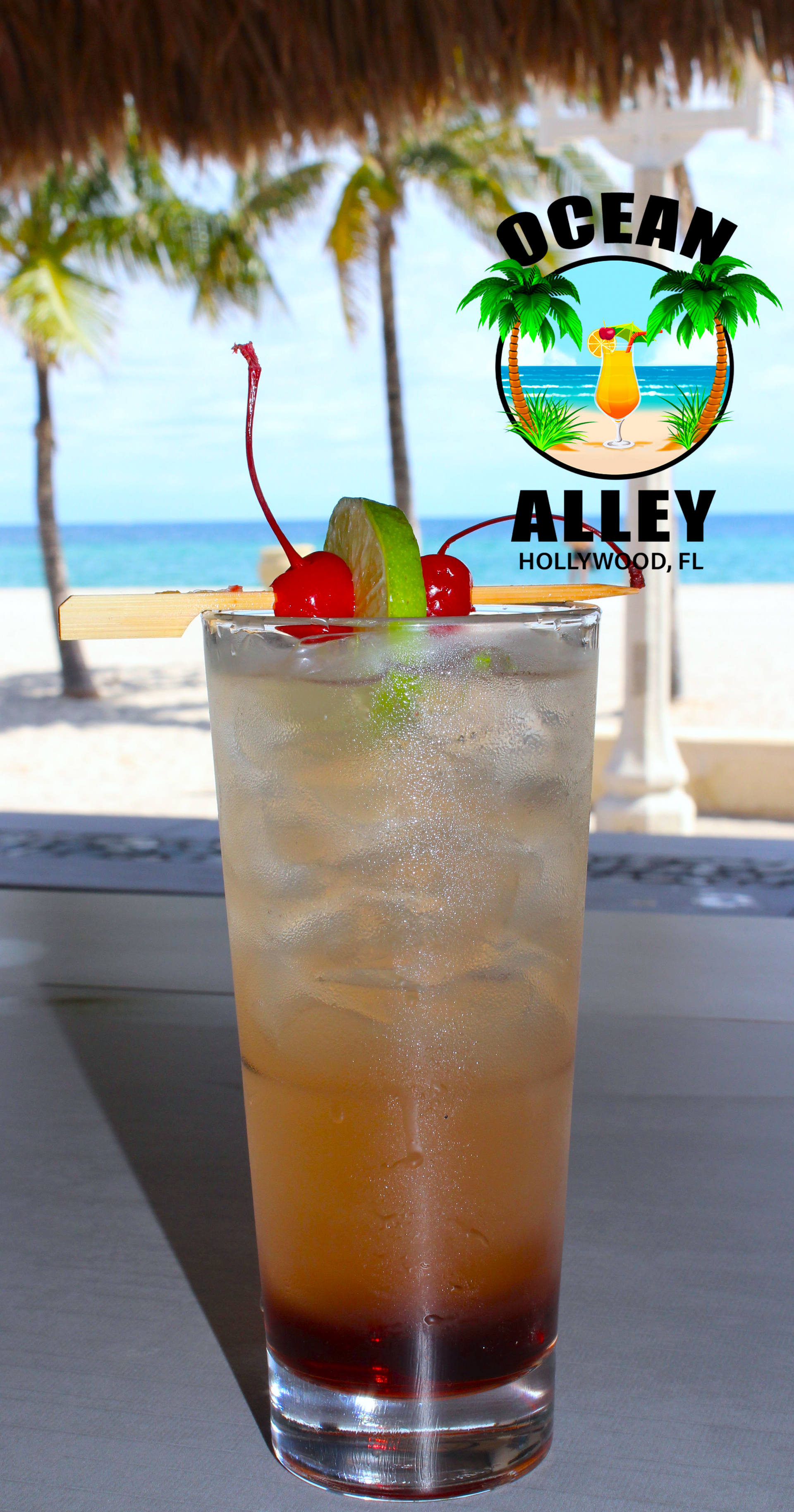 A tall glass of ocean alley cocktail with a cherry on top