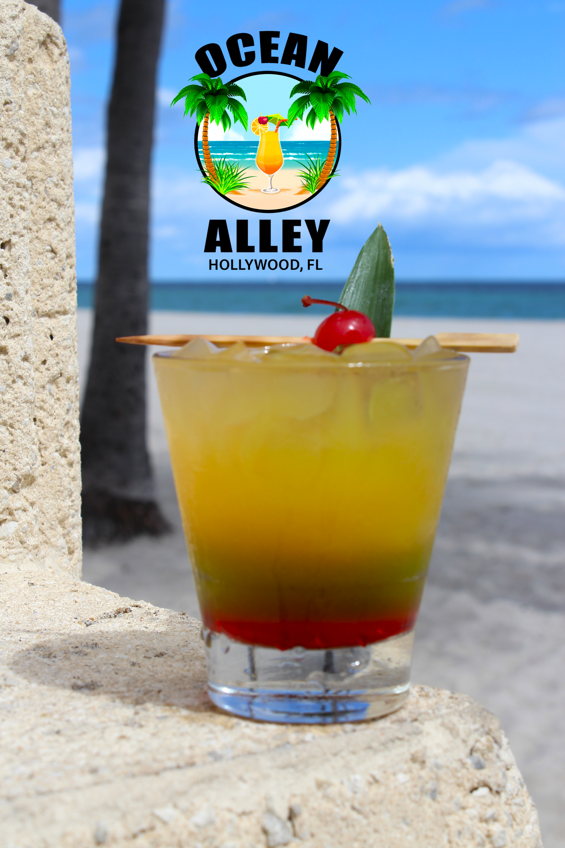 A glass of ocean alley cocktail with a cherry on top