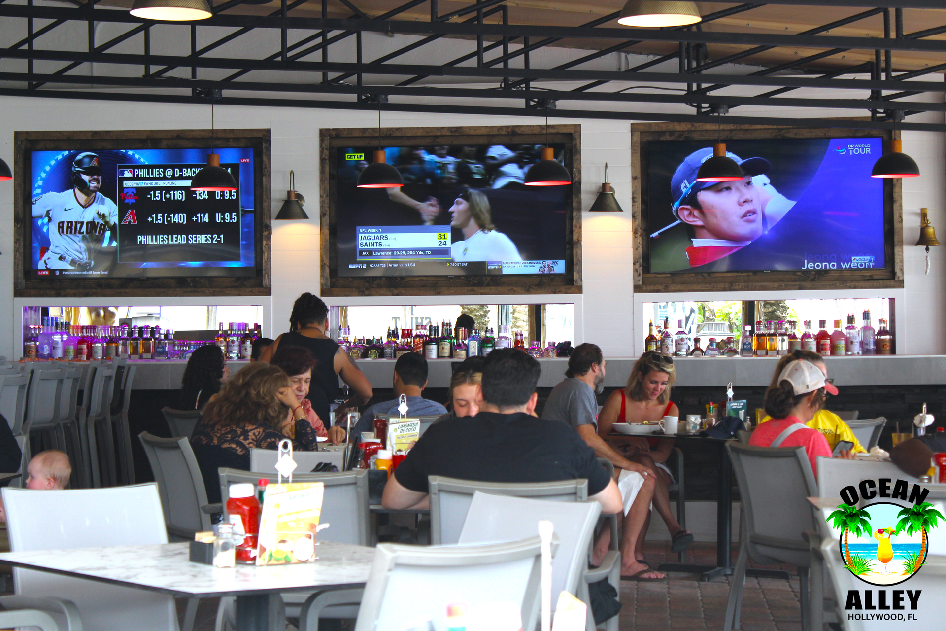 A group of people are sitting at tables in a restaurant watching a baseball game.