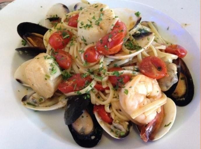A white plate topped with spaghetti clams and tomatoes