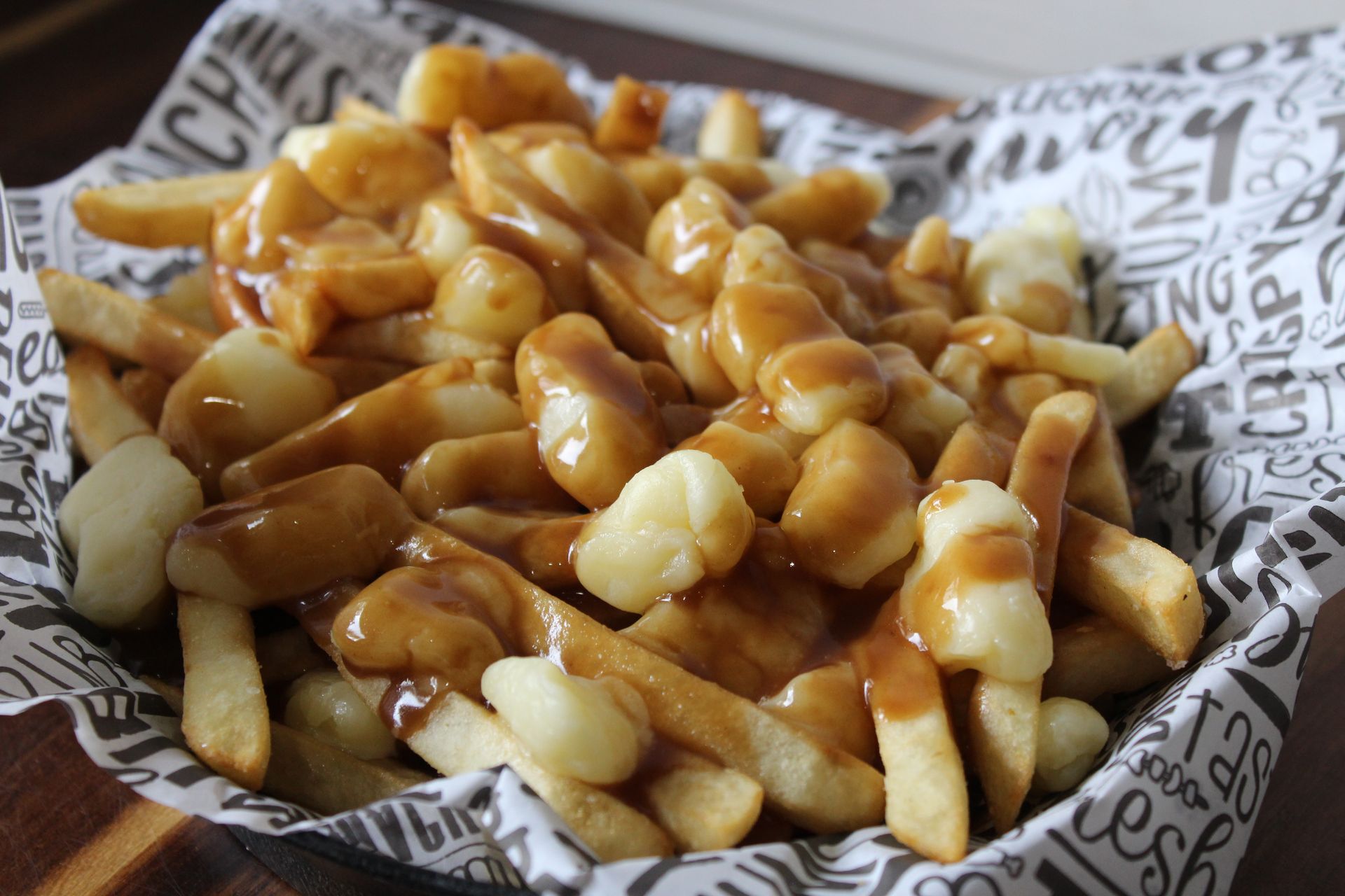 A close up of a bowl of poutine on a table.