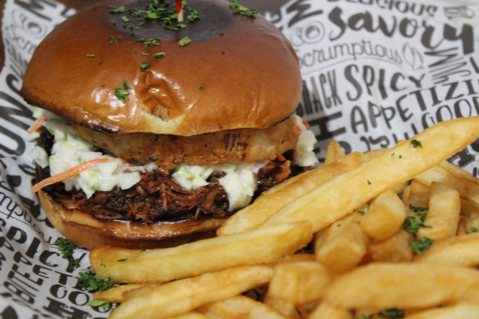 A hamburger and french fries on a paper that says savory