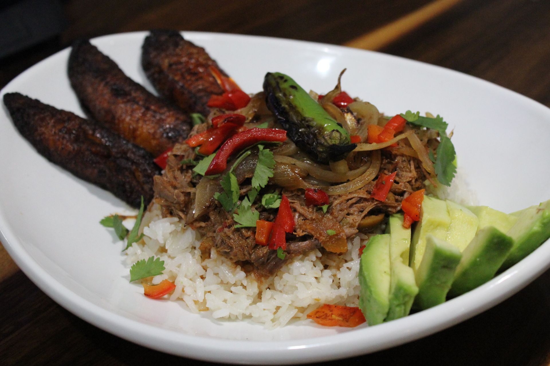 A white plate topped with rice meat and vegetables