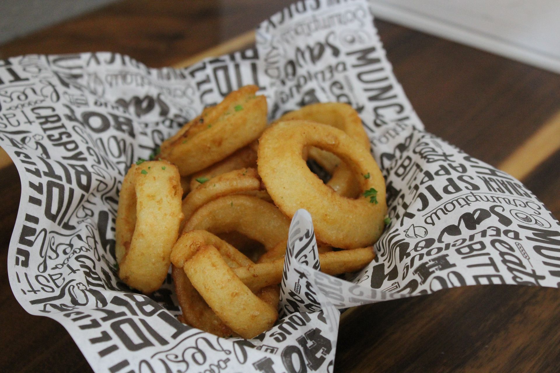 A bowl of onion rings on a piece of paper that says munch