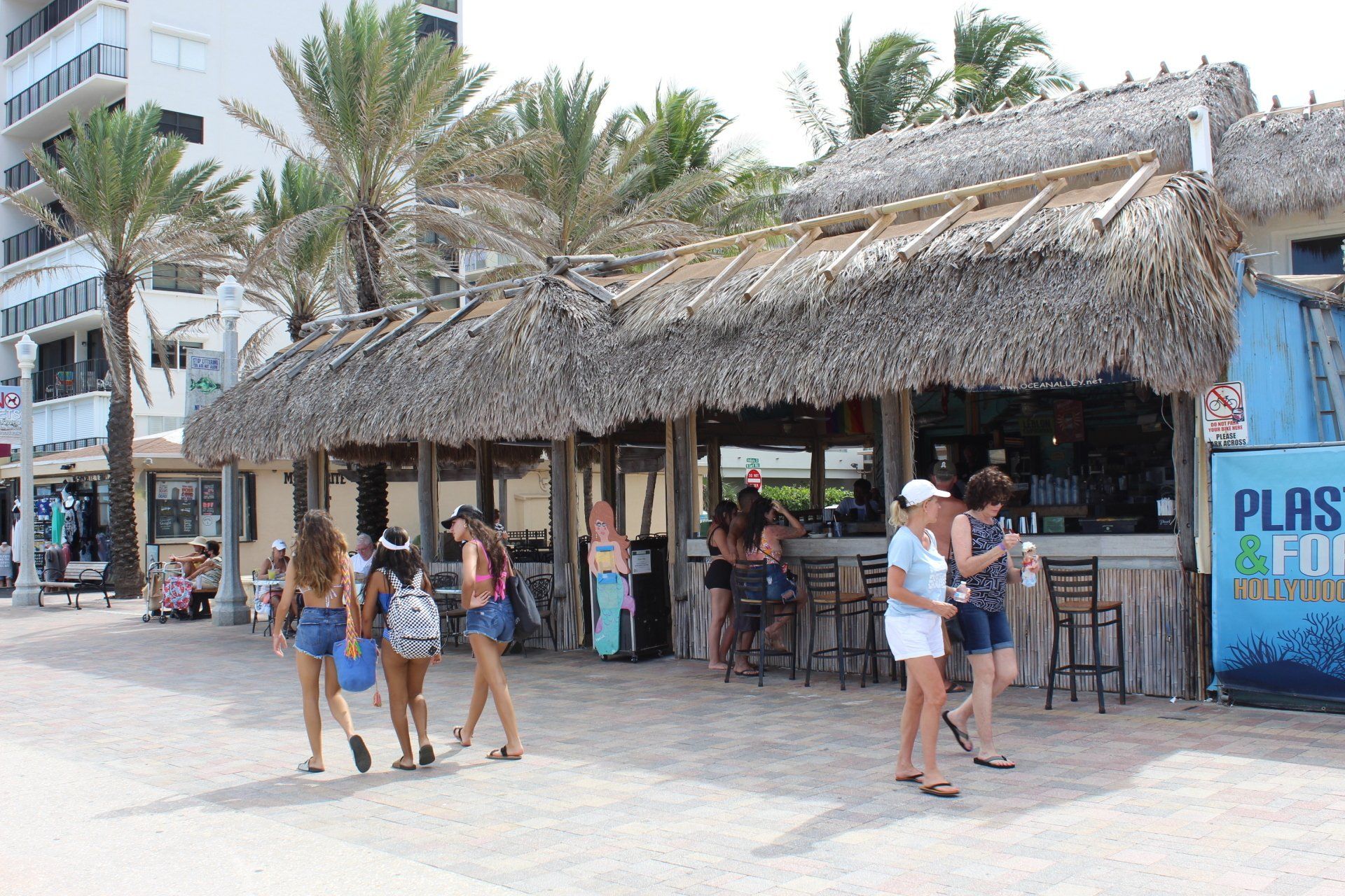 A group of people are walking in front of a thatched hut.