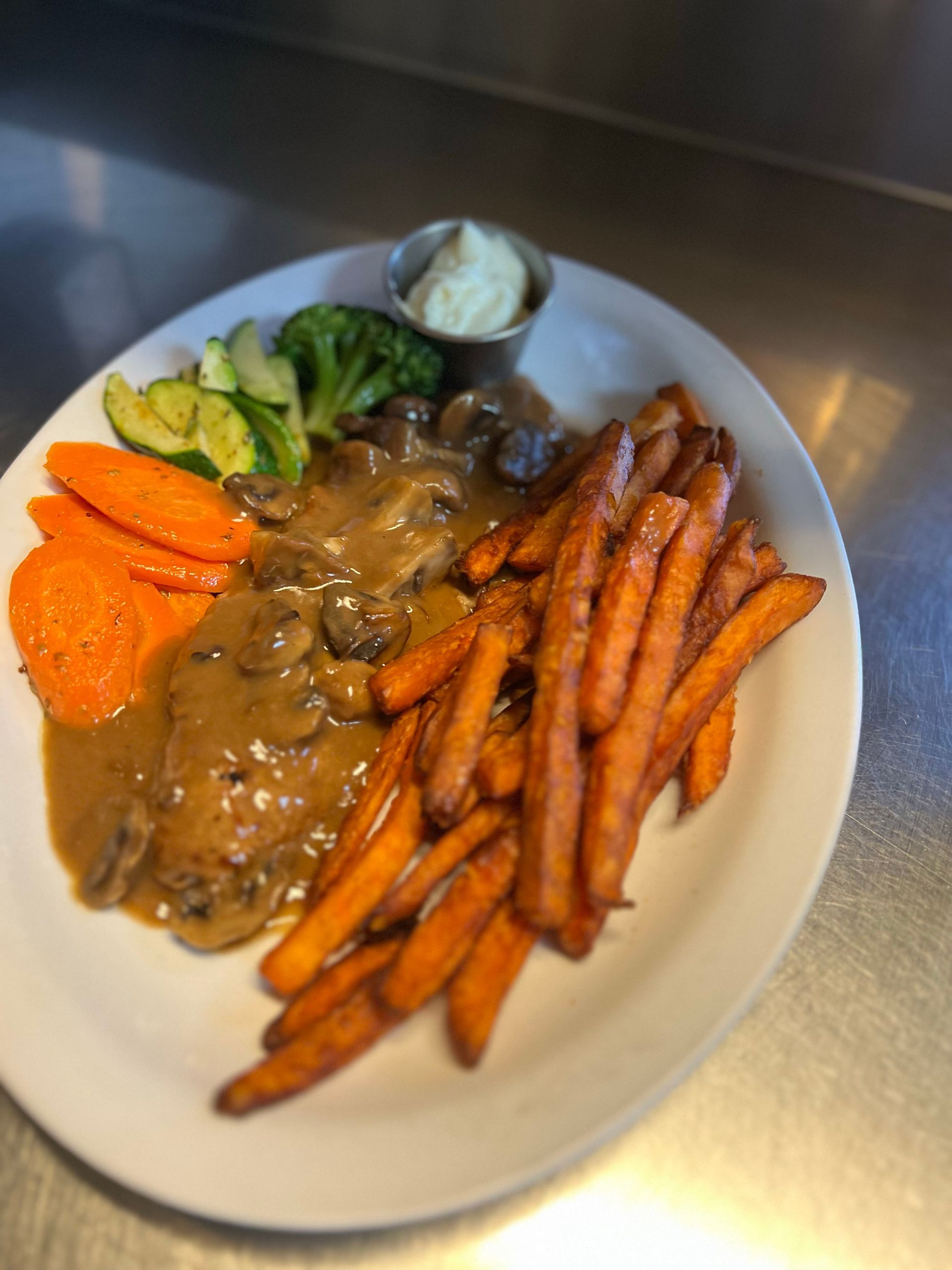Plate of food: Chicken with mushroom gravy, sweet potato fries, vegetables, and dip.