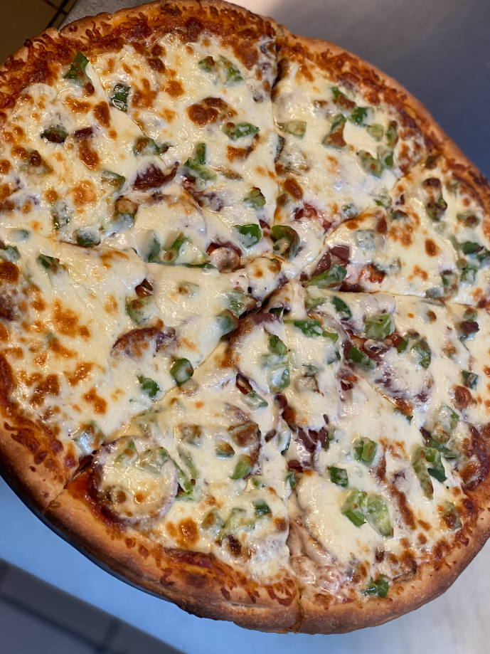 Pizza topped with white cheese, green peppers, and what appears to be bacon.