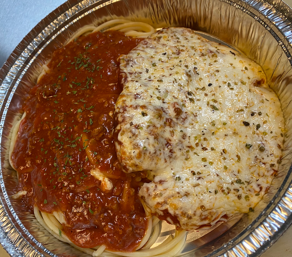 Spaghetti with red sauce and a large, cheese-covered chicken cutlet in a foil container.