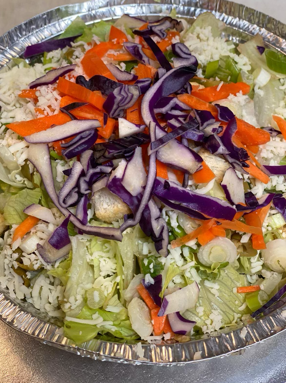 Salad bowl with rice, shredded lettuce, carrots, purple cabbage, and a sprinkle of white.
