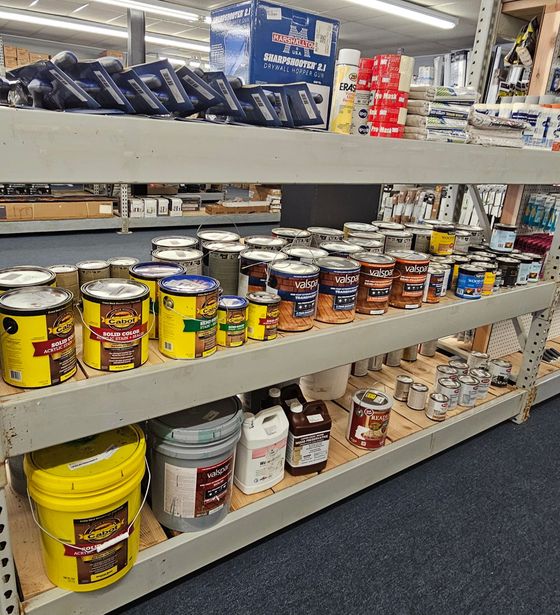 A store shelf filled with lots of buckets and cans of paint.