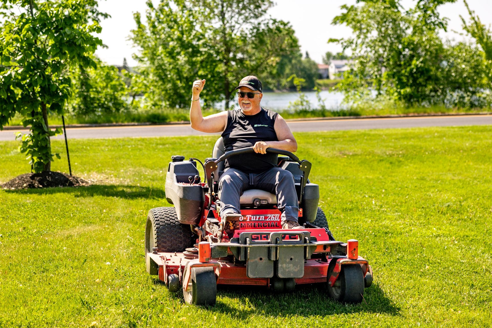 Un homme conduit une tondeuse à gazon sur un champ vert luxuriant.