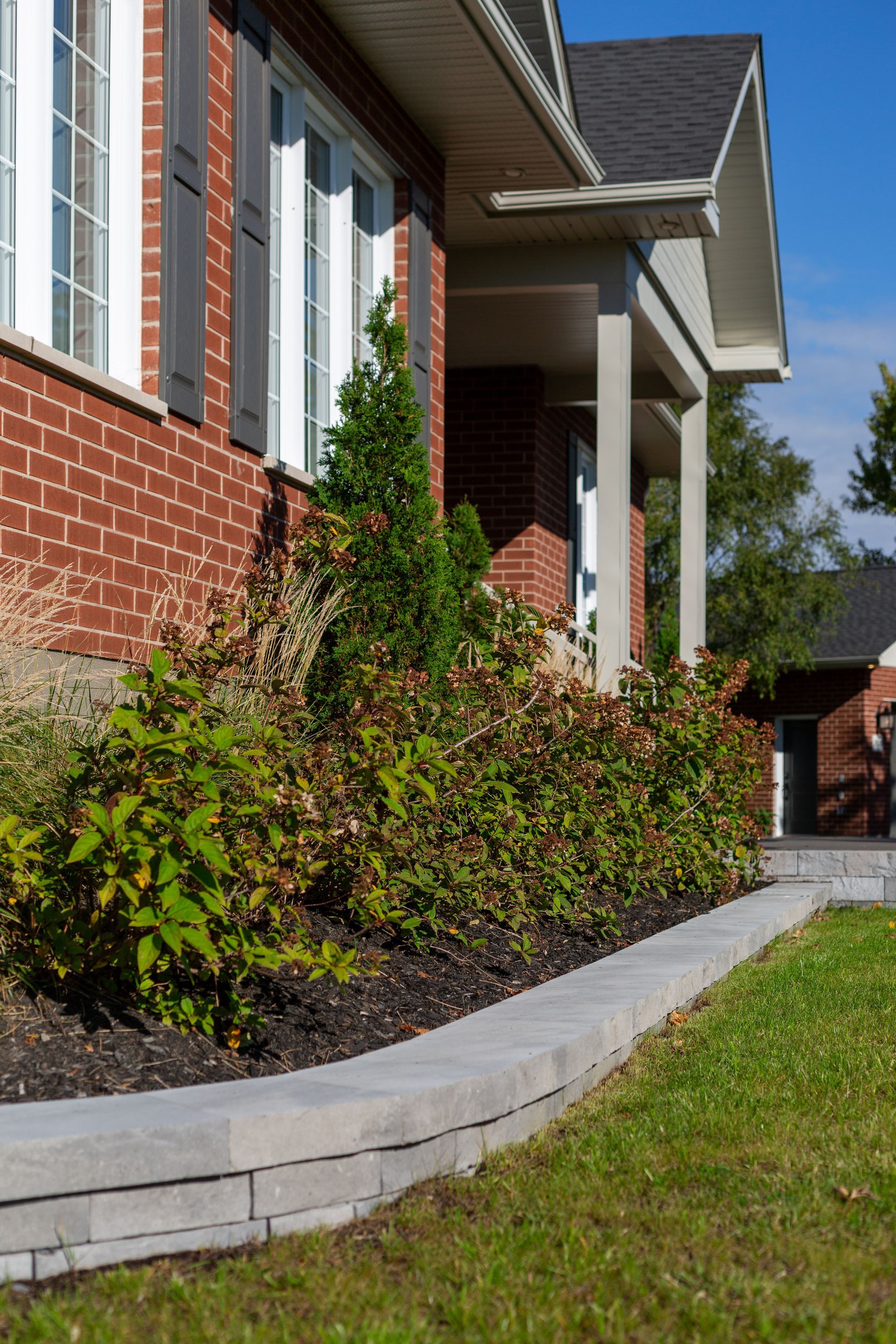 Une maison en briques avec une pelouse verte luxuriante devant elle.