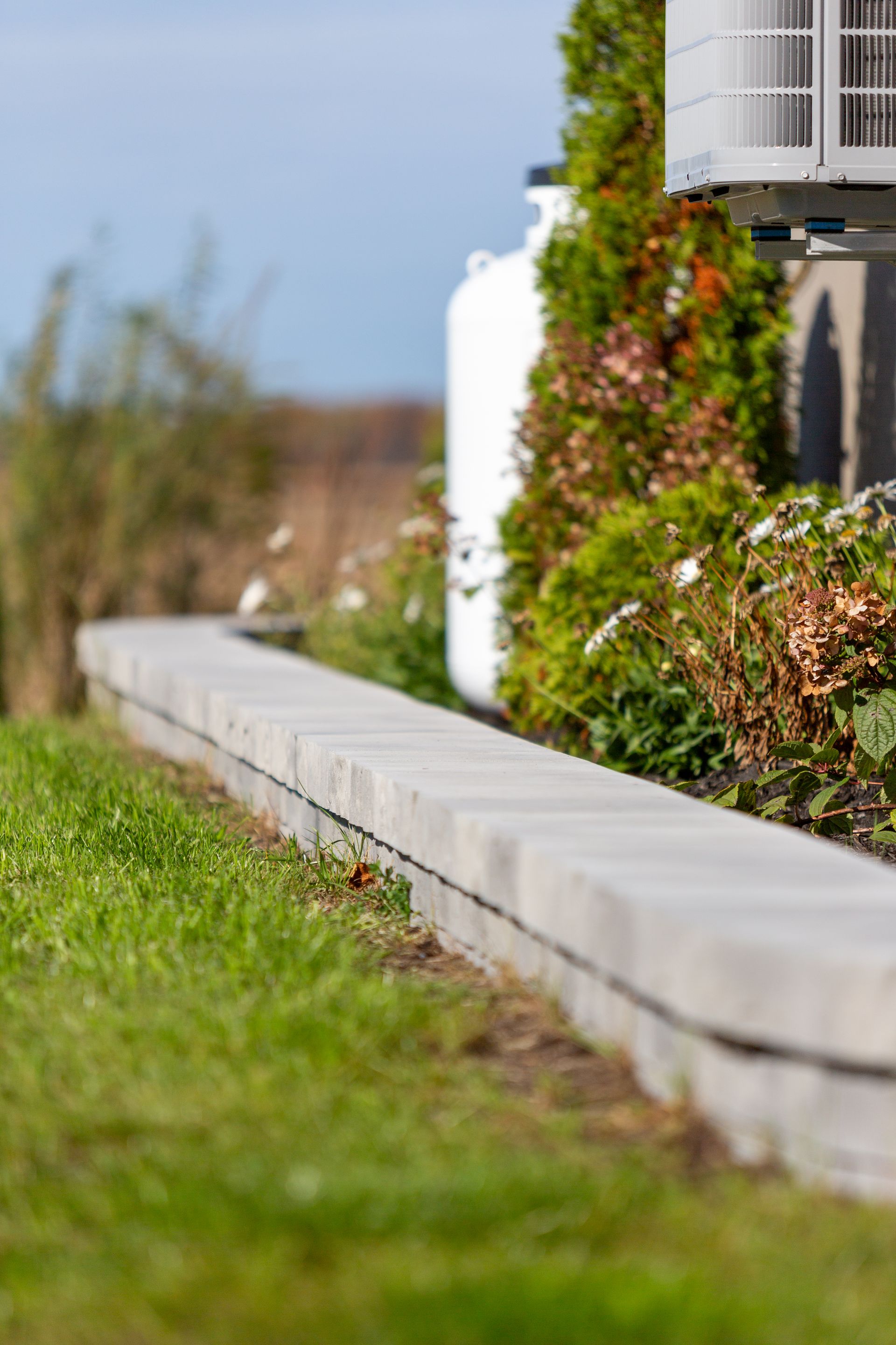Un mur de béton entoure une pelouse verte luxuriante devant une maison.
