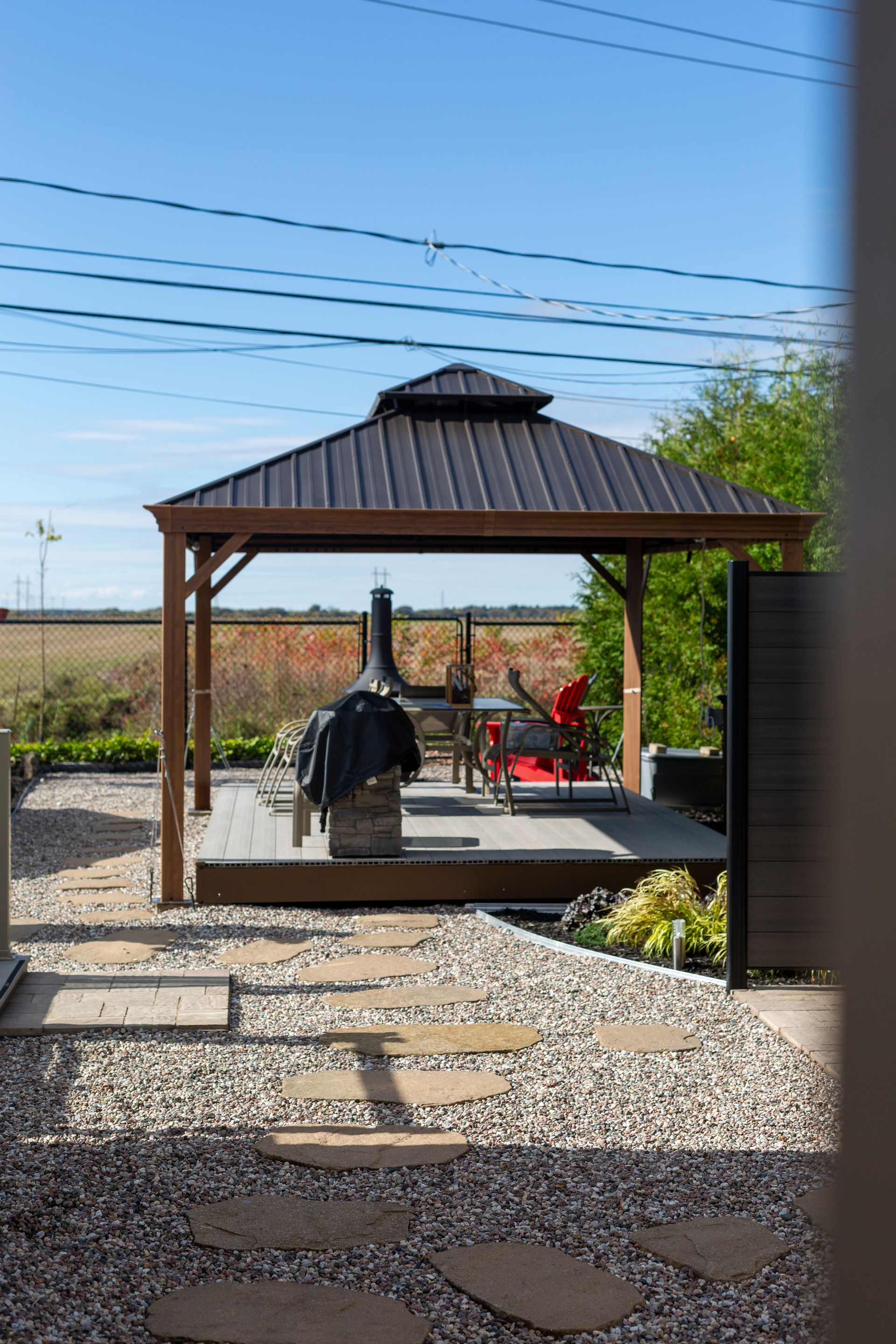 Un belvédère avec un toit noir se trouve au milieu d'une cour de gravier.