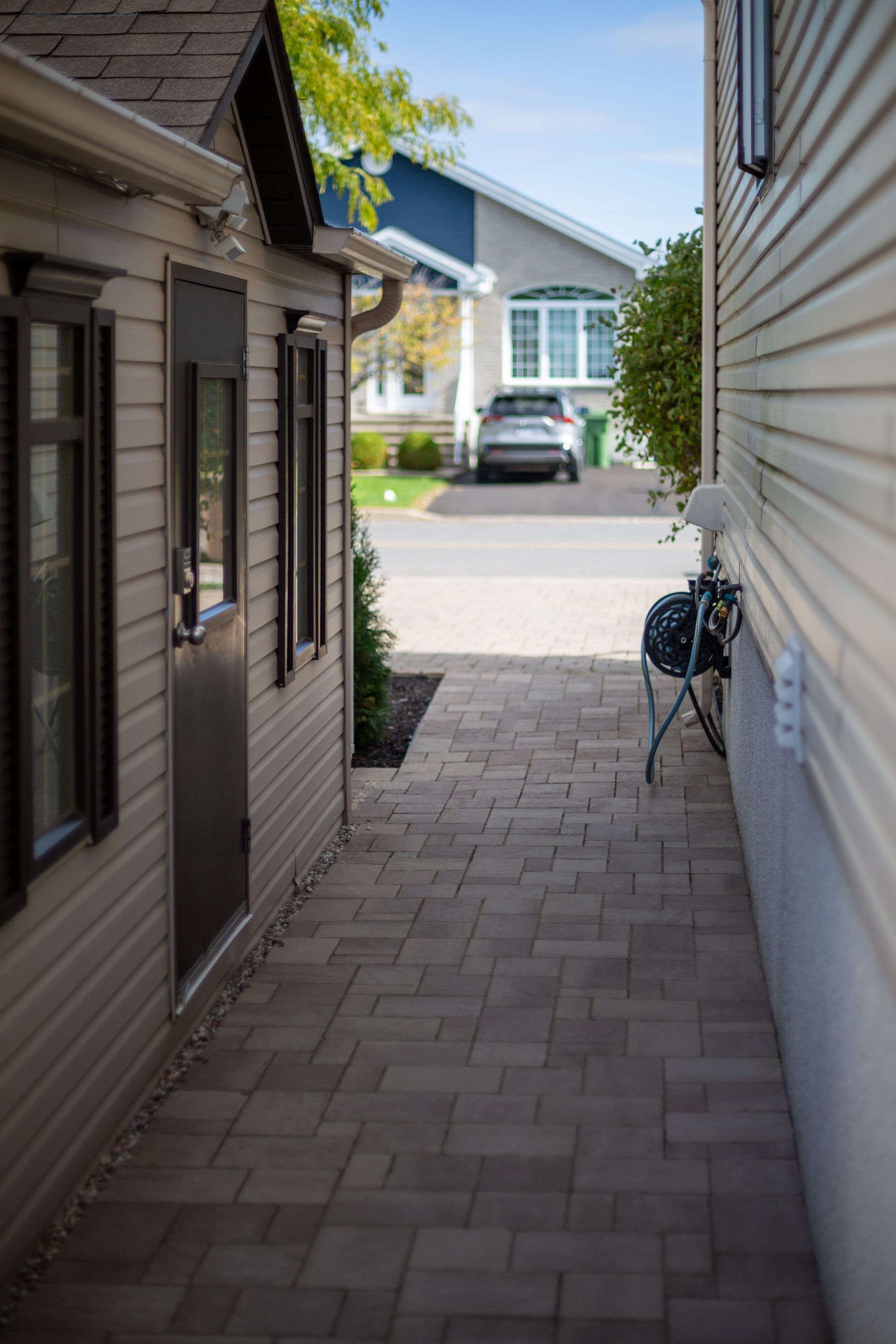 Un passage étroit entre deux maisons avec une voiture garée dans l'allée.