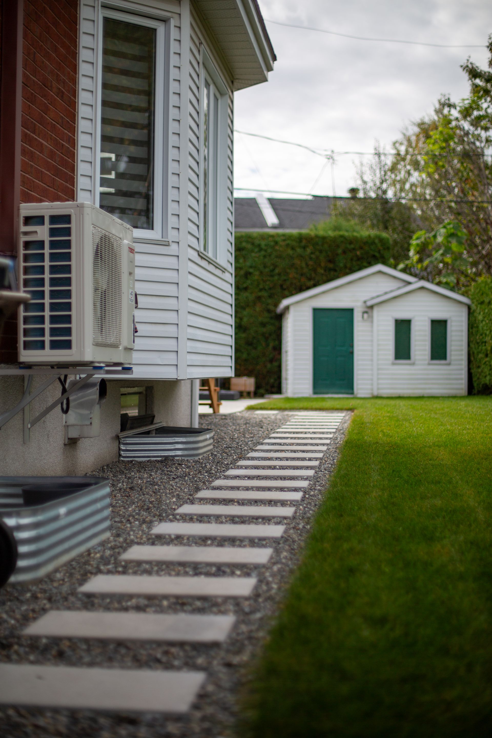 Une maison avec un hangar dans l'arrière-cour et une allée qui y mène.