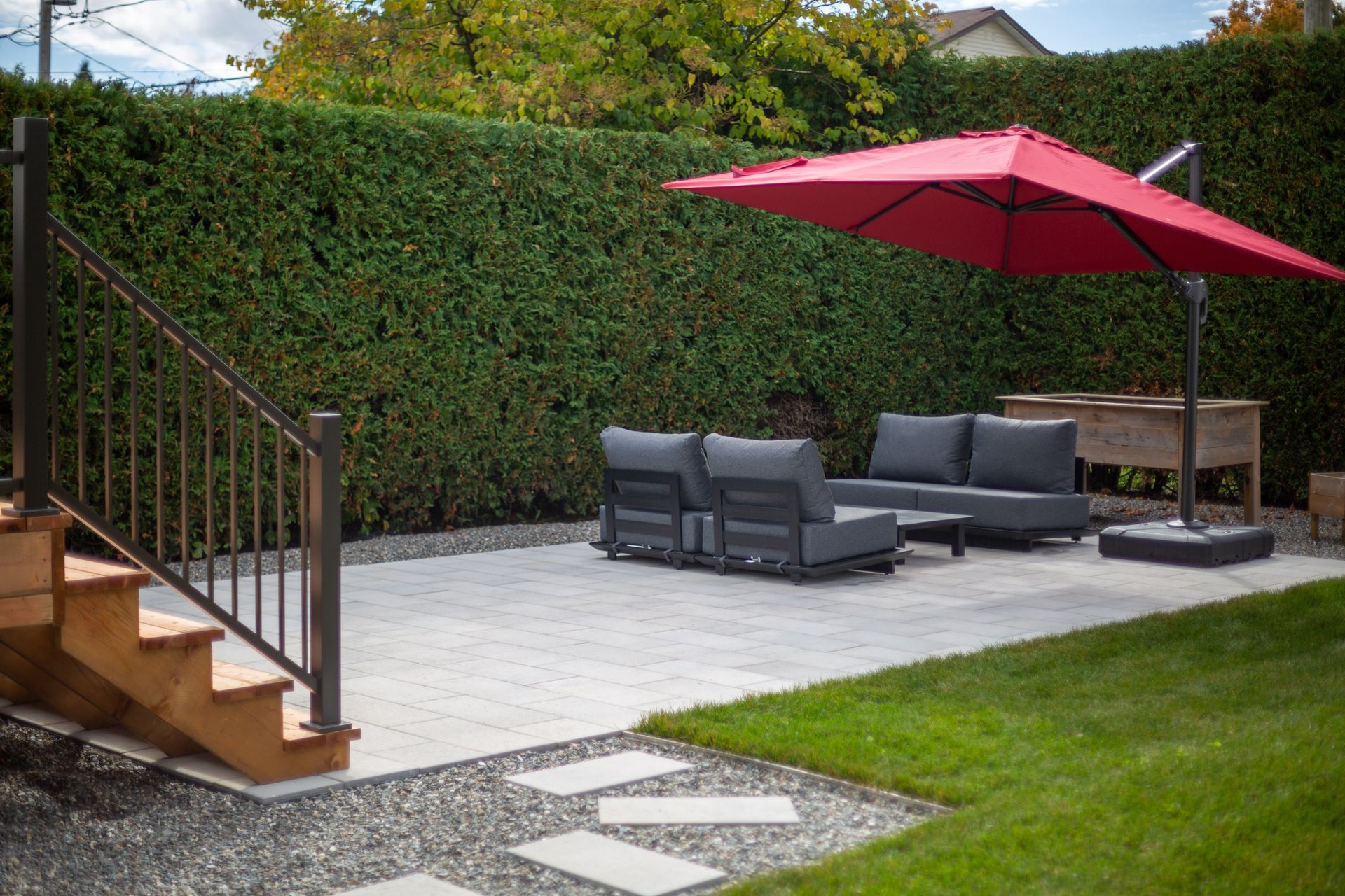 Un patio avec un parasol rouge et un canapé.