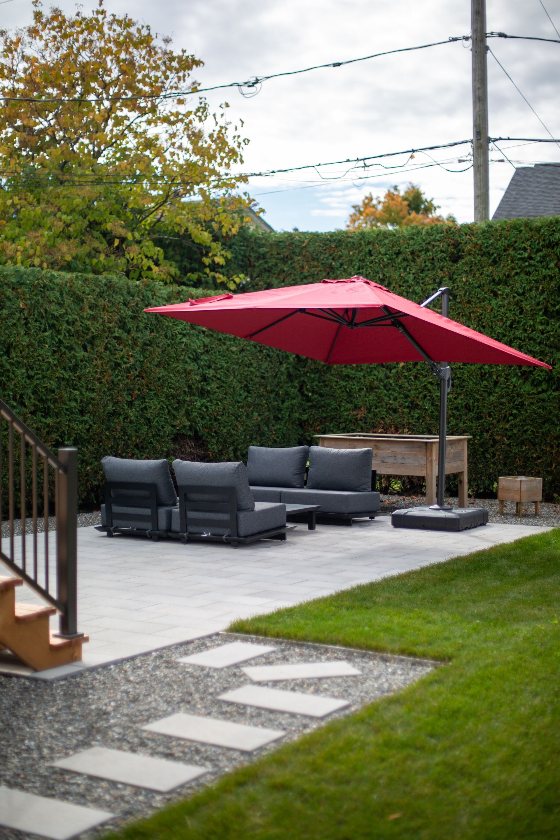 Un patio avec un parasol rouge et un canapé.