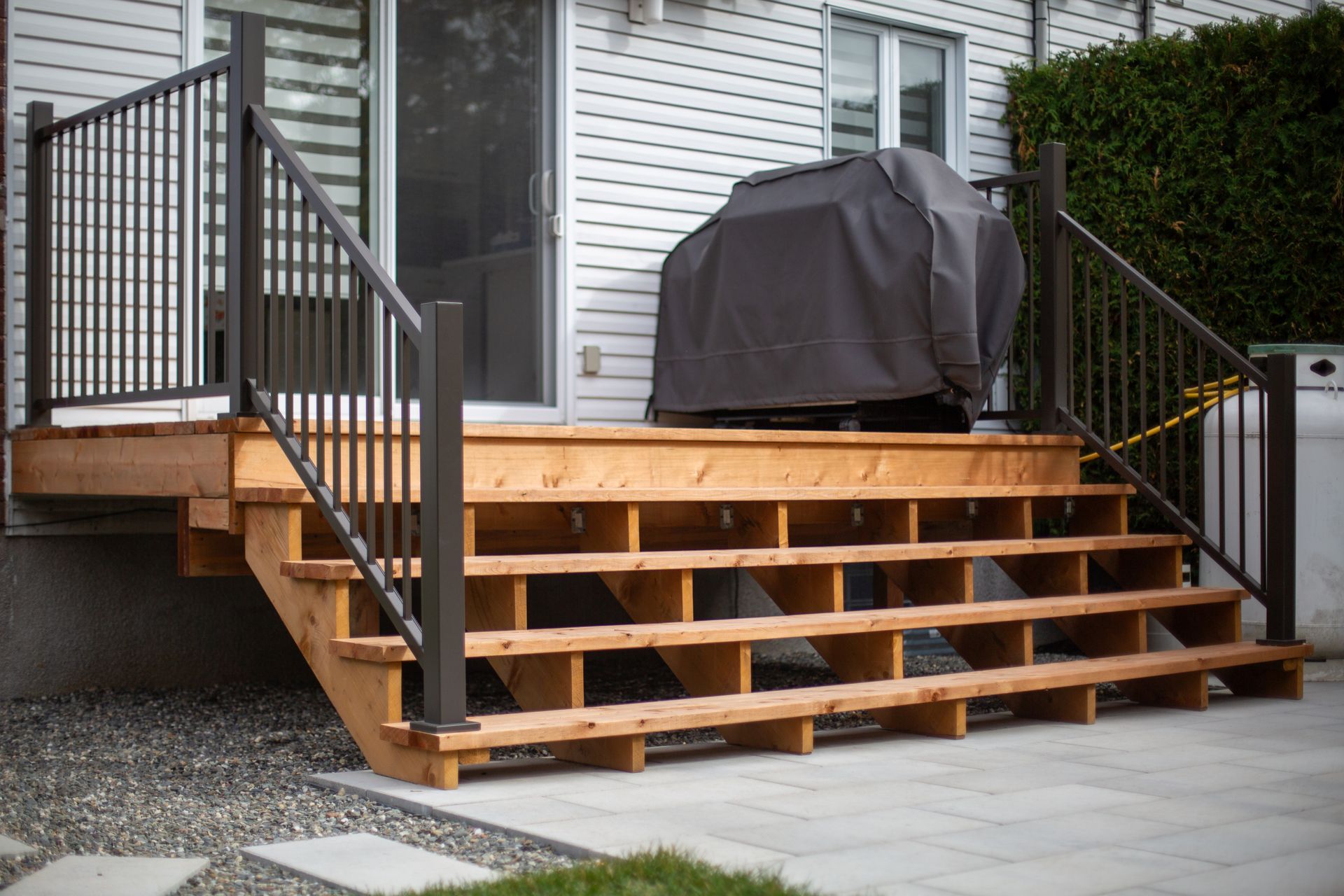 Une terrasse en bois avec des escaliers et un gril dessus.