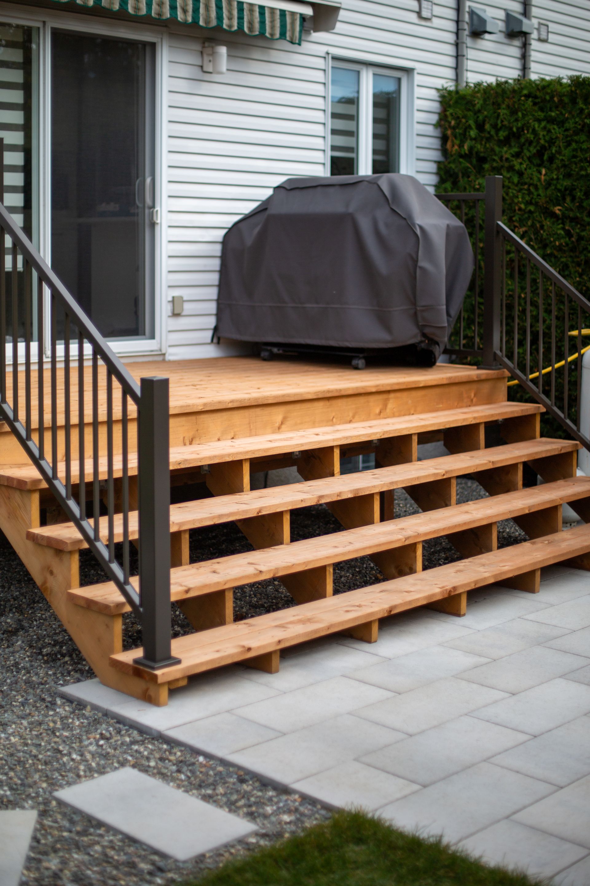 Une terrasse en bois avec des escaliers et un gril dessus.