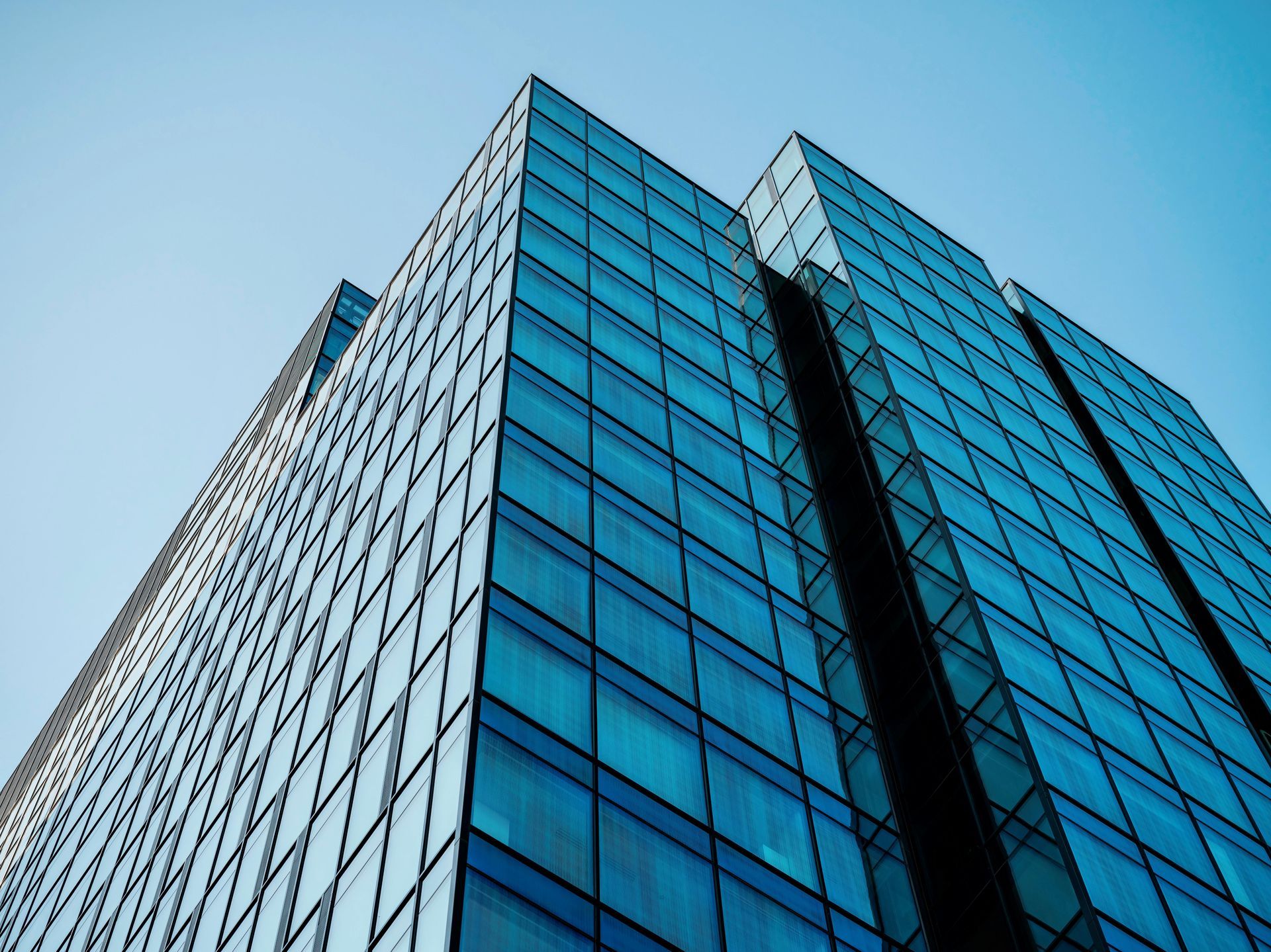 Blue glass skyscraper seen from below against a clear sky