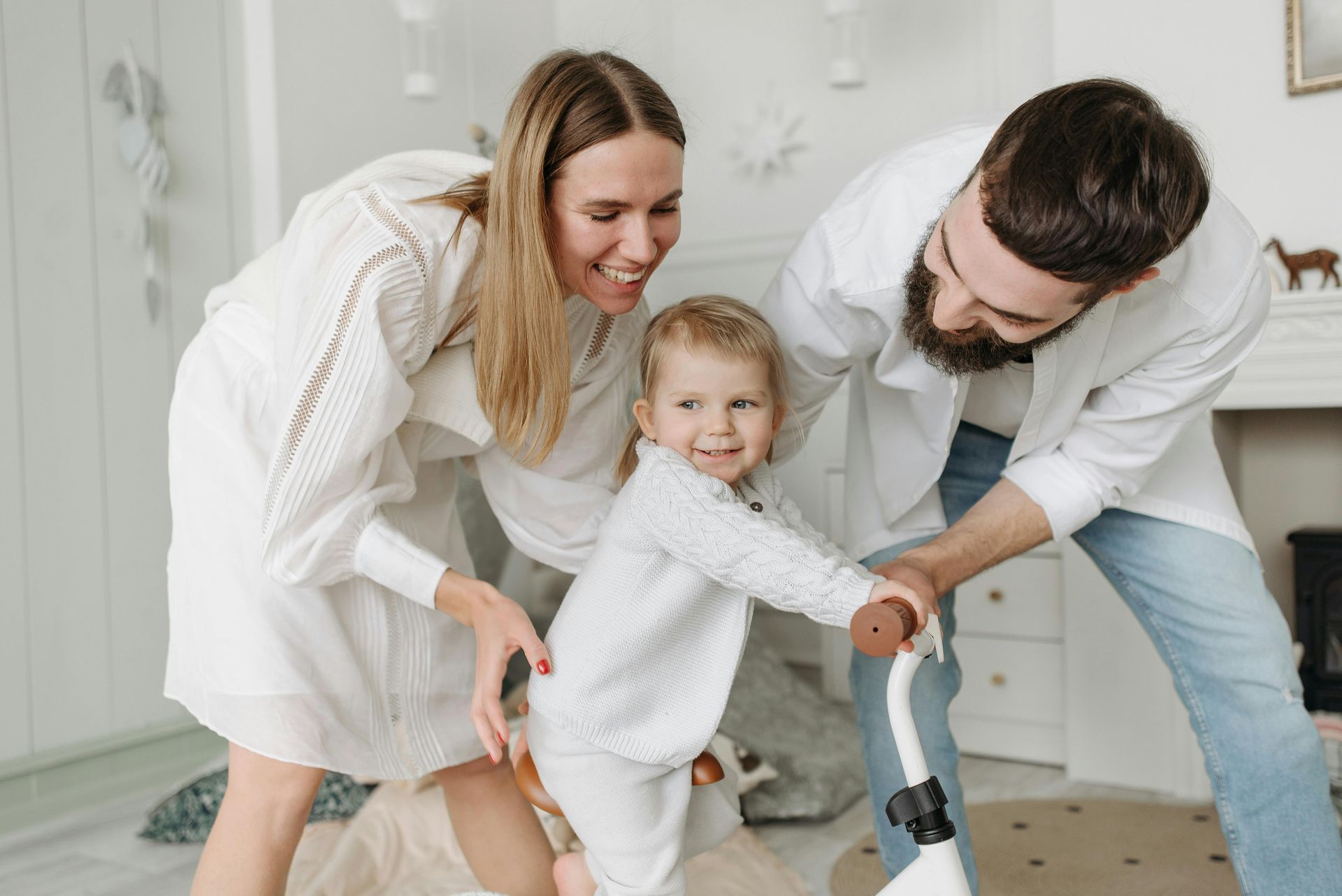 Family smiling and holding a toddler indoors in a bright room